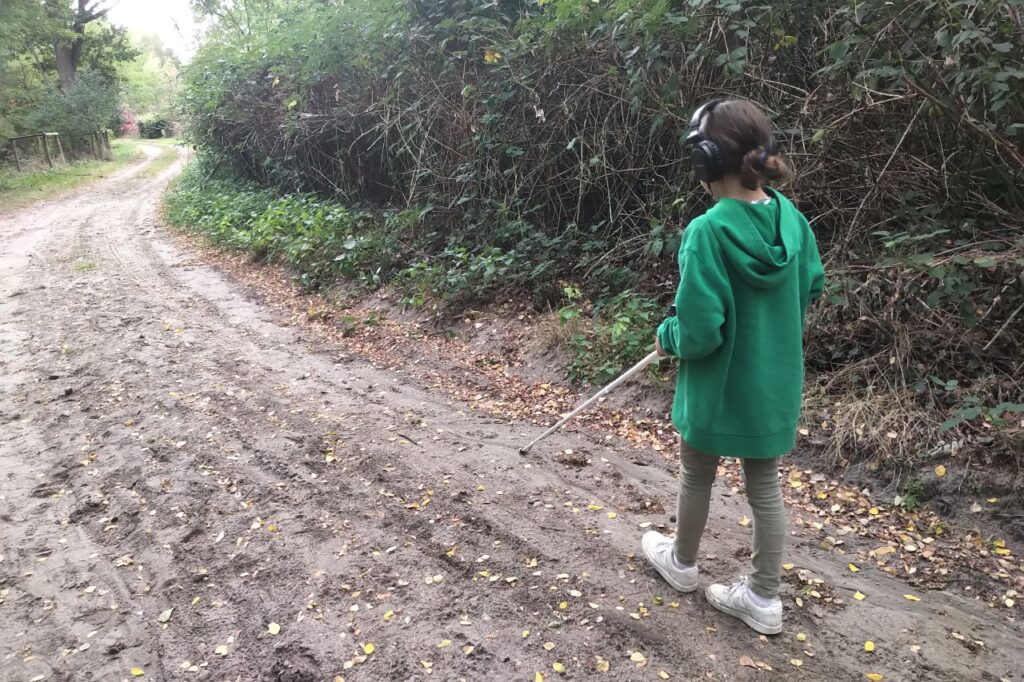 Kind mit einem Blindenstock und Kopfhörern